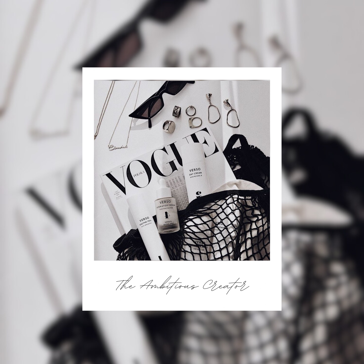 A flatlay of accessories including a vogue magazine, jewellery, skin products and sunglasses in a moody black and white
